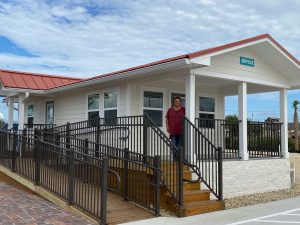 Image of Tangie Horton standing on the front porch of our new RV Park Office.